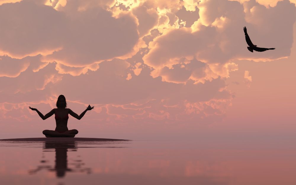 une ombre de femme assise en lotus médite sur un coucher de soleil rosé